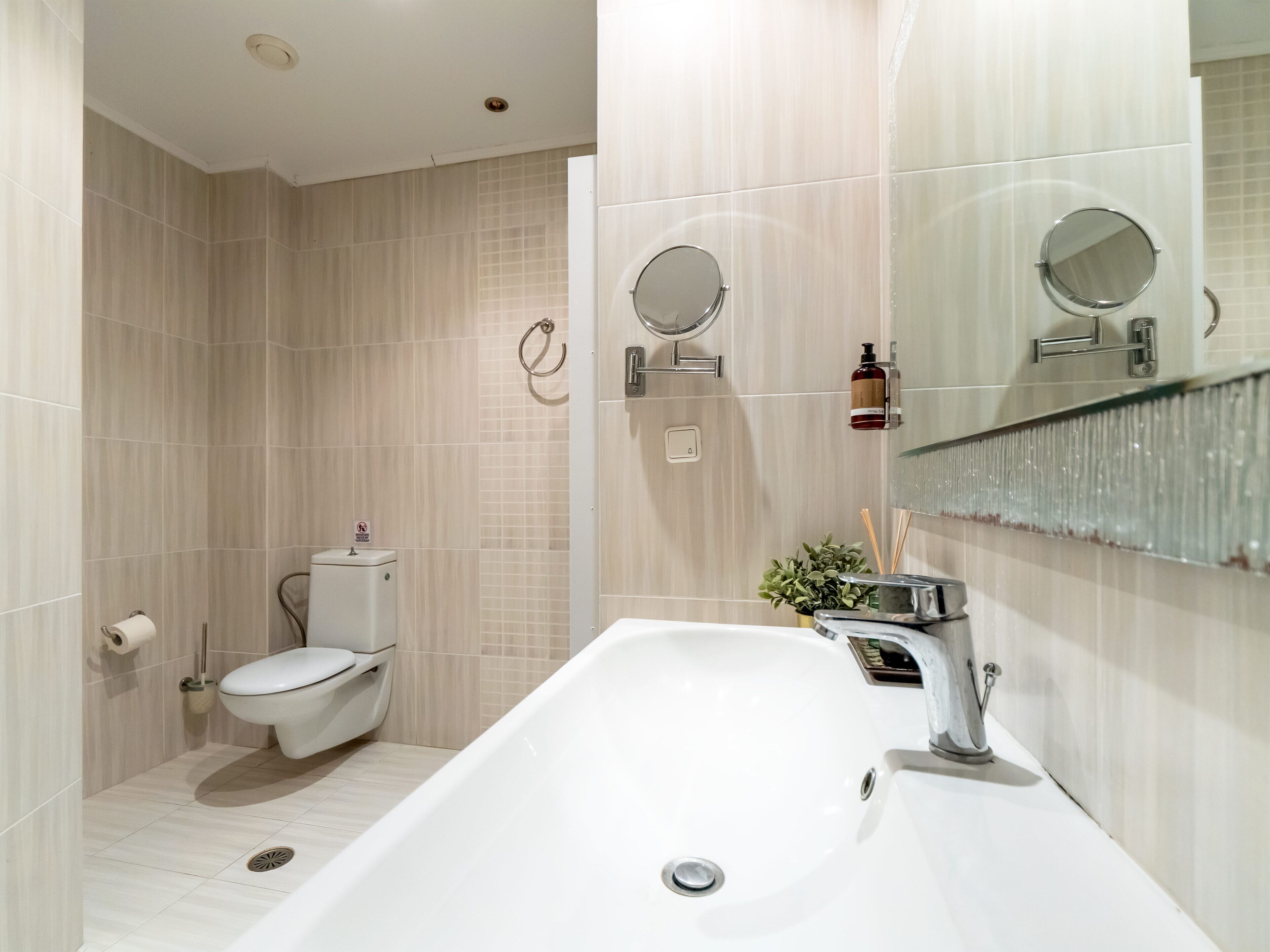 A modern bathroom with a white bathtub, a toilet, and a sink.