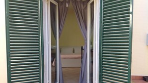 Ein Zimmer mit einem Bett, einem kleinen Tisch und einem Fenster mit Vorhängen.