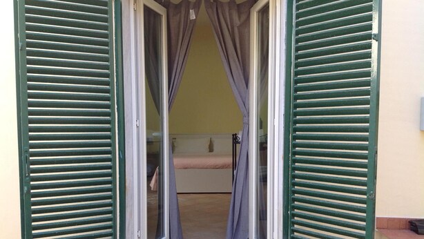 A room with a bed, a small table, and a window with curtains.