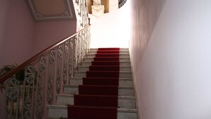 A staircase with red carpeted steps and ornate metal railings.