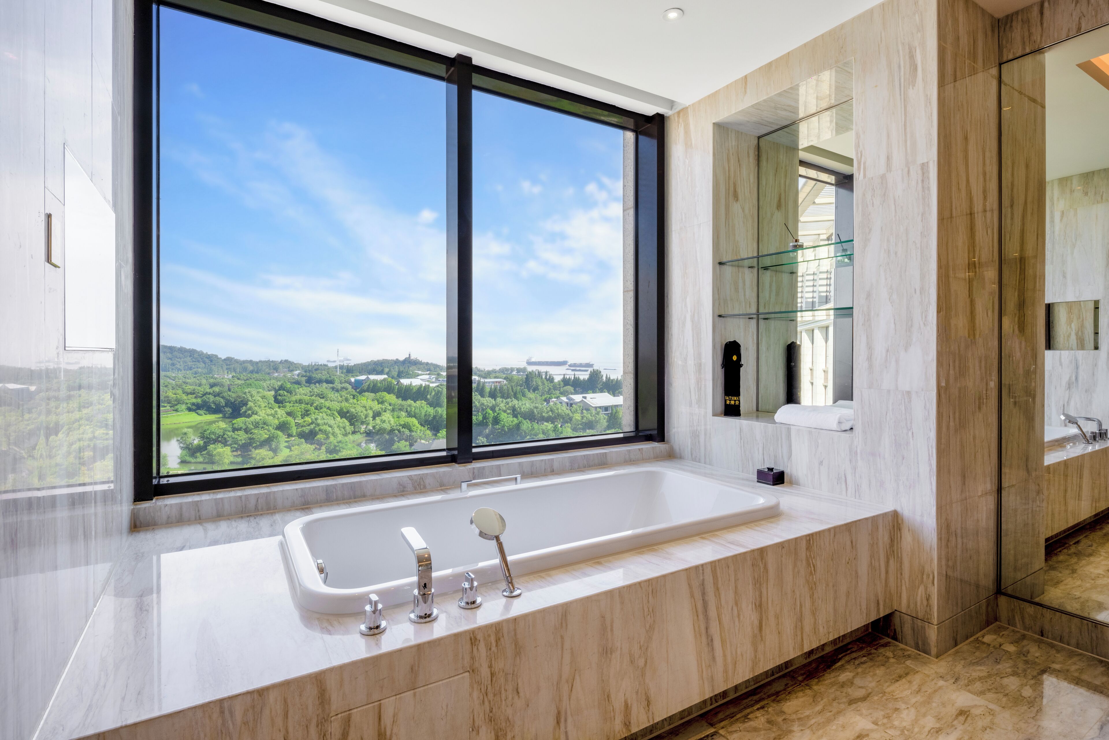A modern bathroom with a large window, a bathtub, and a glass shower enclosure.