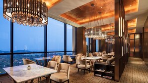 A modern dining area with large windows, multiple tables, and contemporary chandeliers. - InterContinental Nantong by IHG (Nantong)
