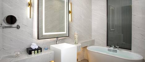 A modern bathroom with a large mirror, a white sink, a bathtub, and a glass shower enclosure.