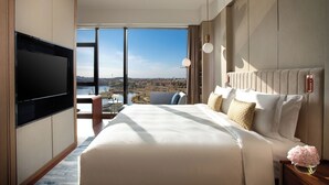 A modern hotel room with a large bed, a flat-screen TV, and a view of a cityscape through large windows. - InterContinental Nantong by IHG (Nantong)