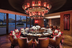 A dining area with a round table, red upholstered chairs, and a central chandelier. - InterContinental Nantong by IHG (Nantong)