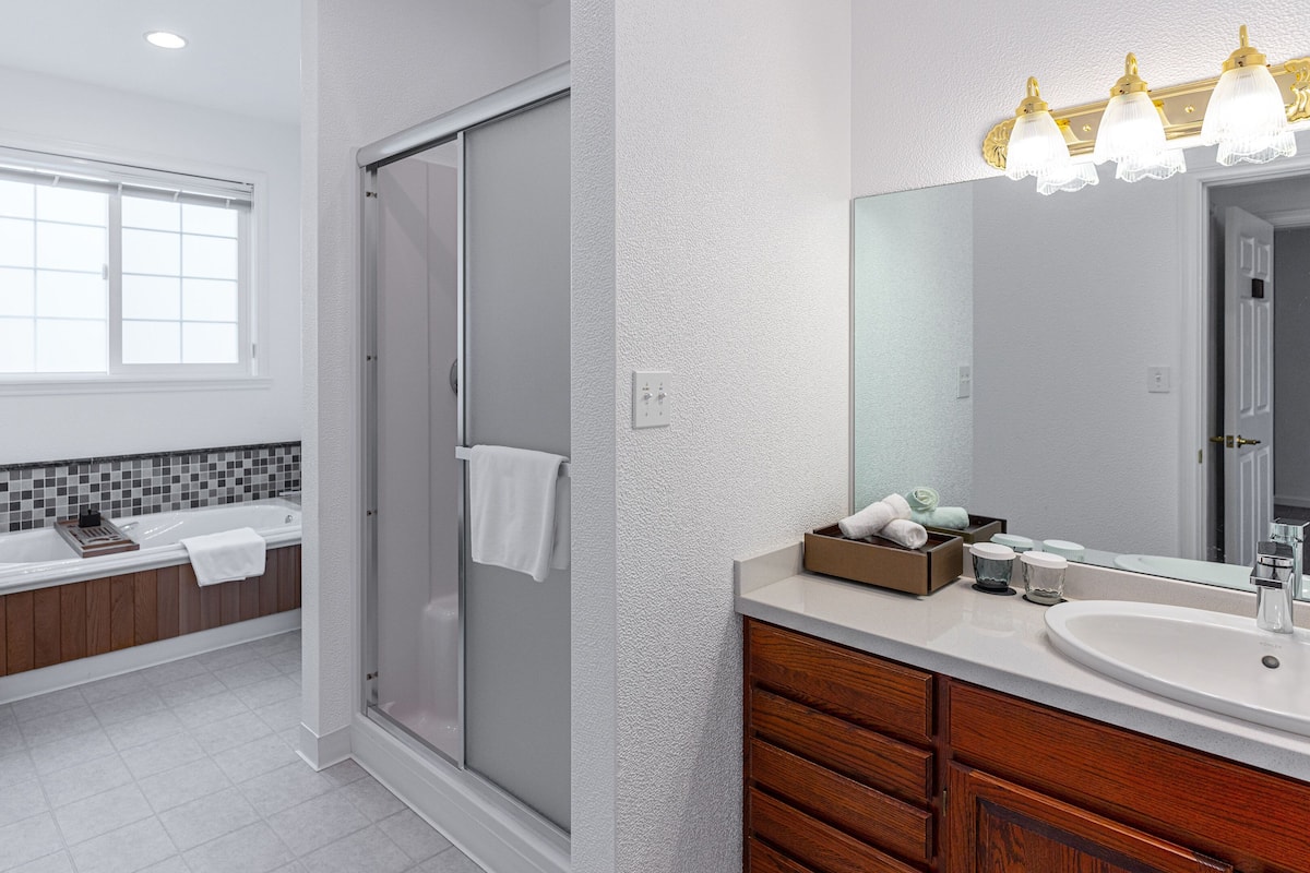 Een moderne badkamer met een douche, een bad, een wastafelmeubel en een grote spiegel.