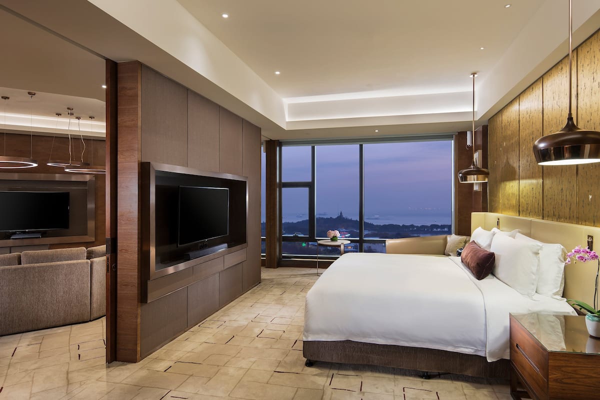 Een moderne hotelkamer met een grote televisie, comfortabele zithoek, een bed en uitzicht op de stad.