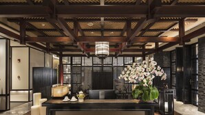 A reception area with a wooden ceiling, a reception desk, a potted orchid, and a black partition. - InterContinental Nantong by IHG (Nantong)