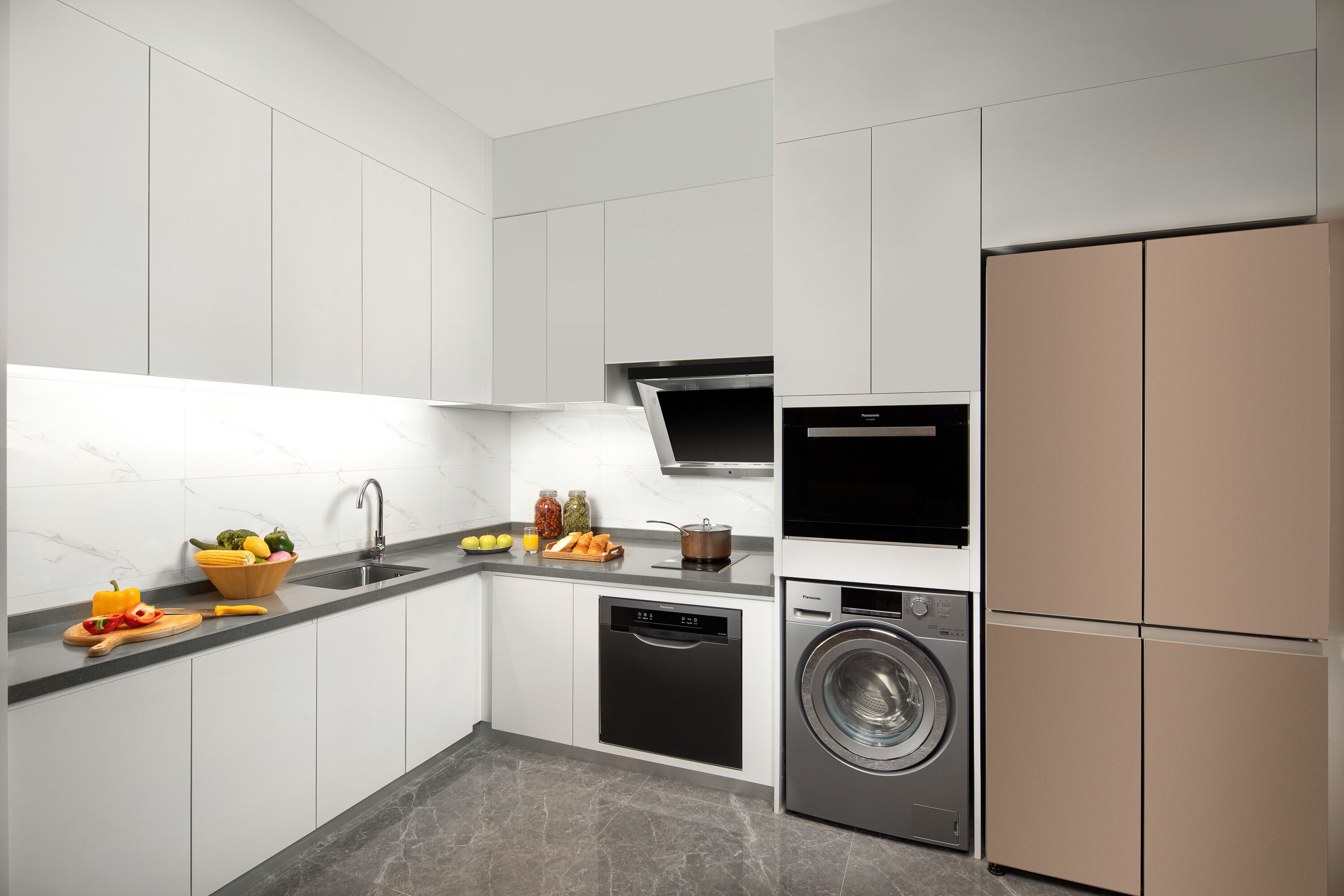Une cuisine moderne avec des meubles blancs, un lave-vaisselle noir, un lave-linge et un réfrigérateur.