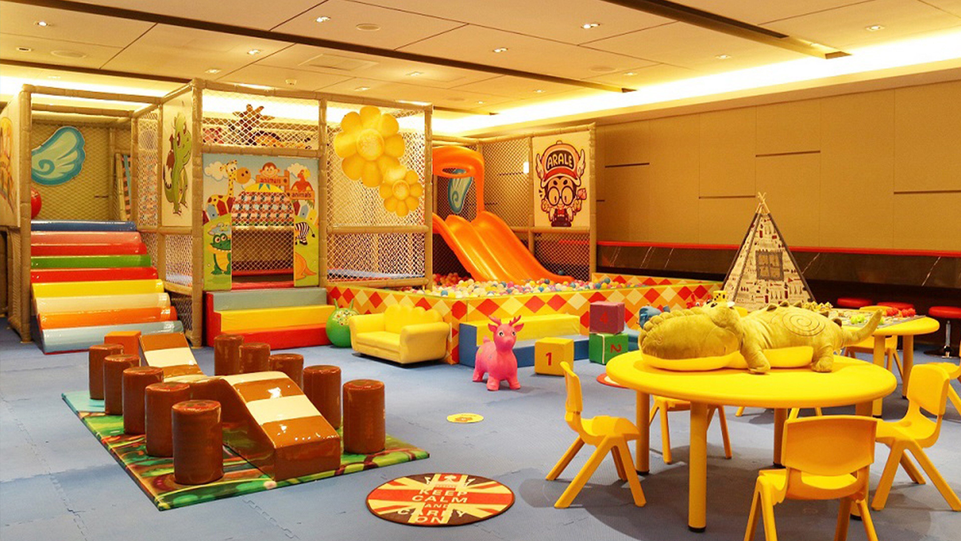 A children's play area with colorful play structures, a slide, and seating areas.