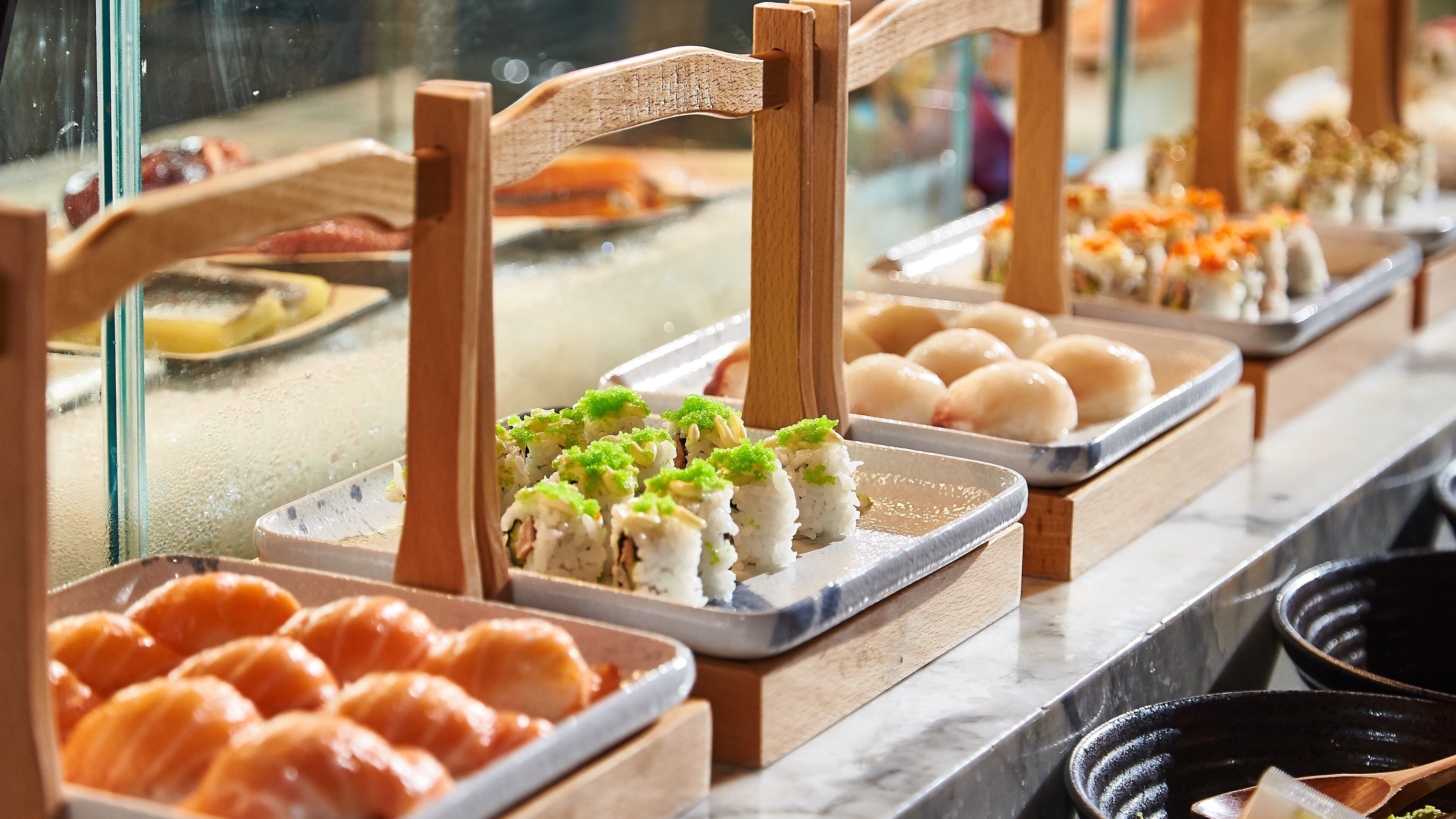 A buffet with various food items, including sushi and other dishes, displayed on wooden stands.