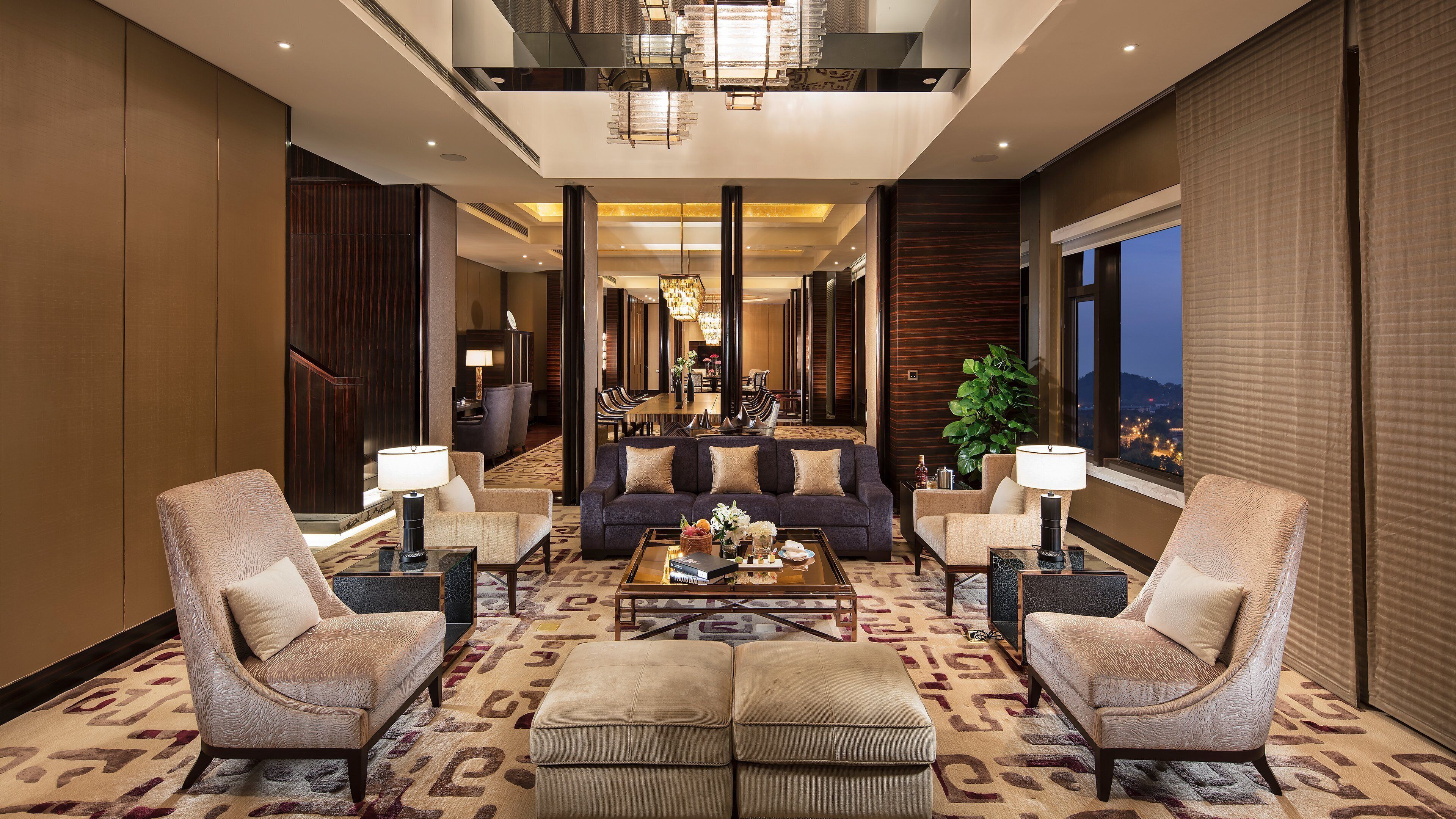 A spacious lobby with a sofa, two armchairs, a coffee table, and a dining area in the background.