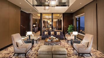 A spacious lobby with a sofa, two armchairs, a coffee table, and a dining area in the background.
