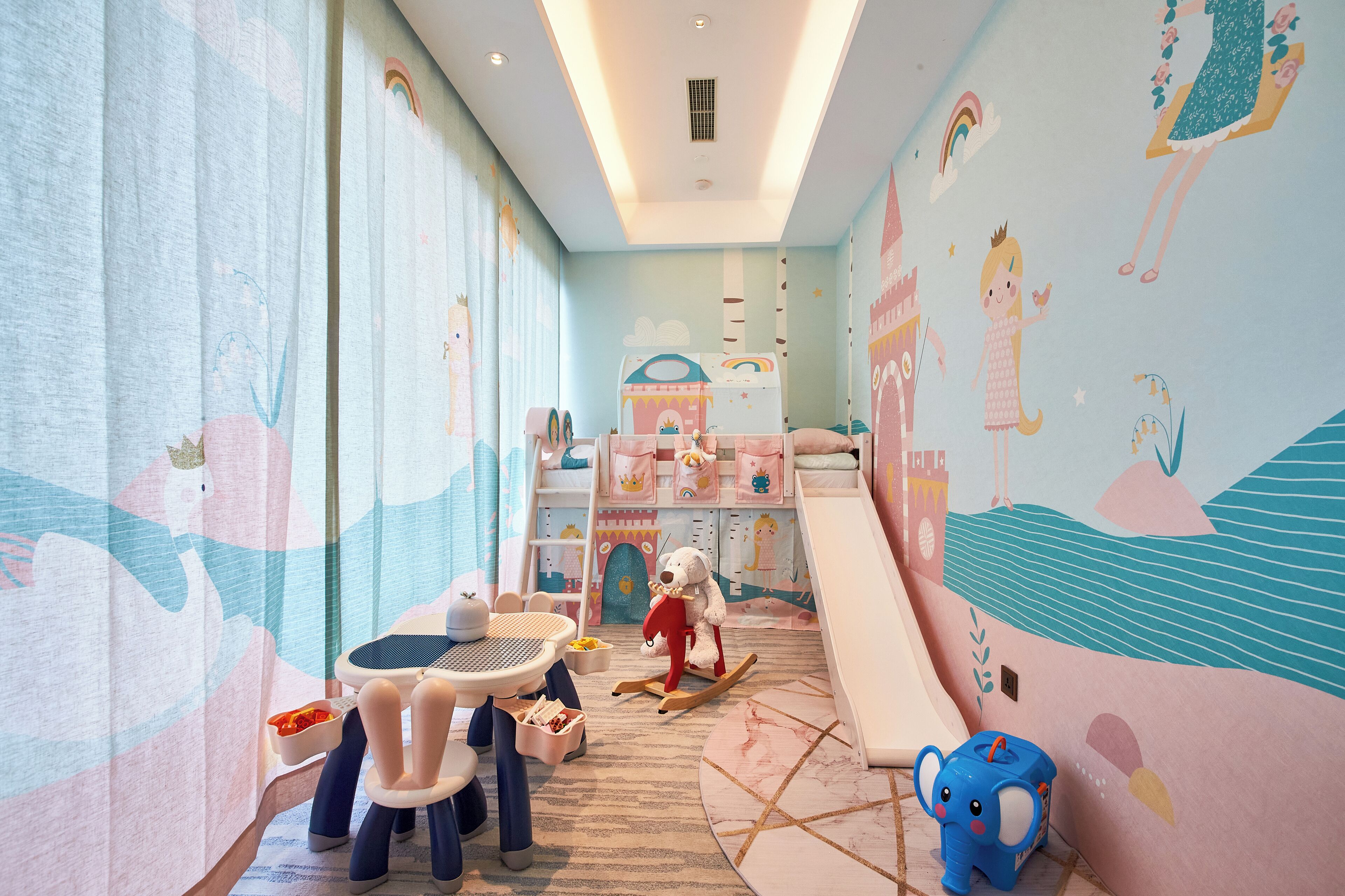 Une salle de jeux pour enfants avec un lit superposé, une table avec des chaises et un cheval à bascule.