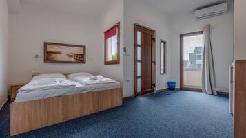 Una habitación de hotel con cama, un cuadro, una puerta y un equipo de aire acondicionado.