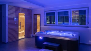 Une salle de spa moderne dotée d’un jacuzzi, de murs recouverts de panneaux en bois et d’une fenêtre avec des stores.