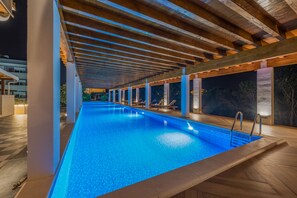 Une piscine intérieure dotée d’un sol carrelé et d’une structure de plafond en bois.