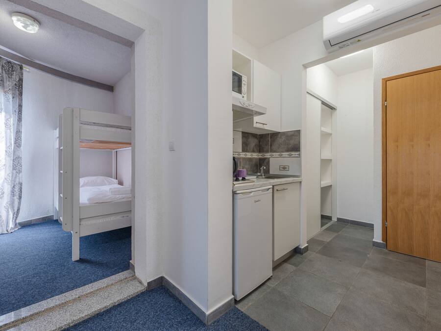 Una habitación pequeña con literas, un kitchenette y una puerta de madera.