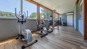 Une salle de sport équipée de matériel d’exercice, dotée de grandes fenêtres et d’un plancher en bois.