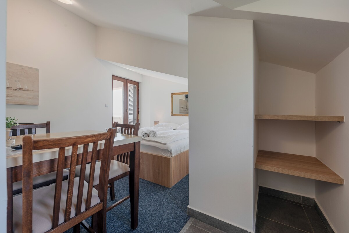 Un dormitorio con una cama, una silla de madera, un escritorio y una mesita.