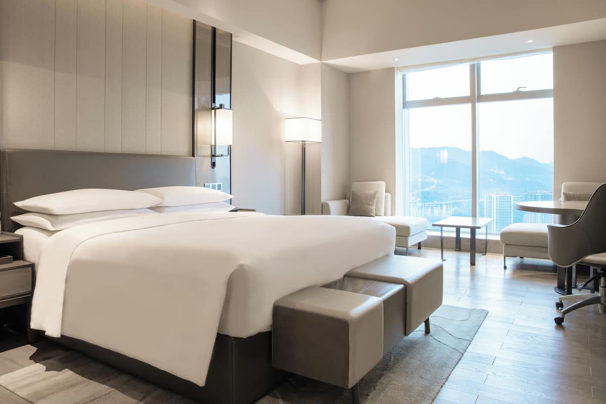 A modern hotel room with a large bed, a desk, and a chair.