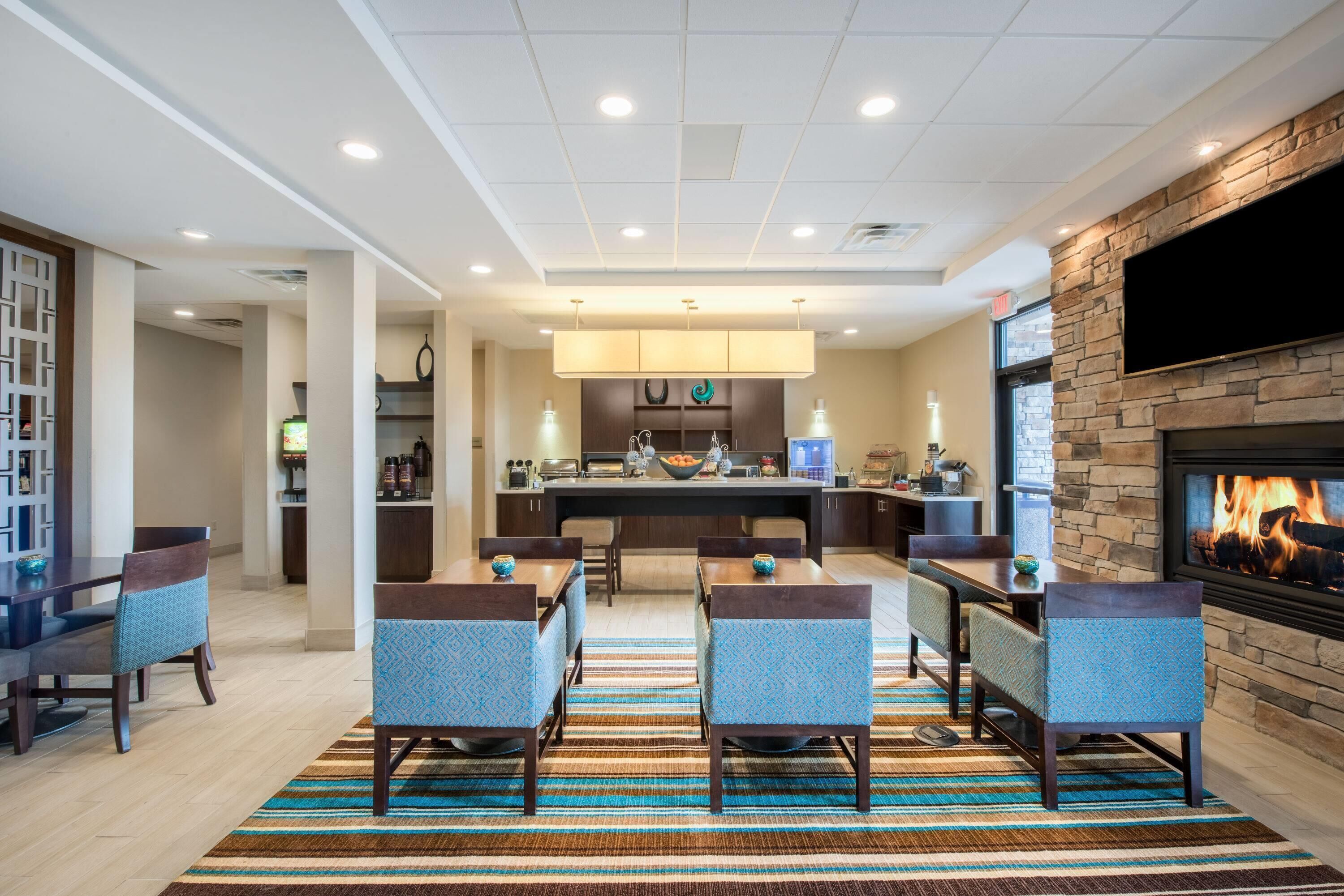A modern kitchen with a central island, a dining area with chairs, and a fireplace.