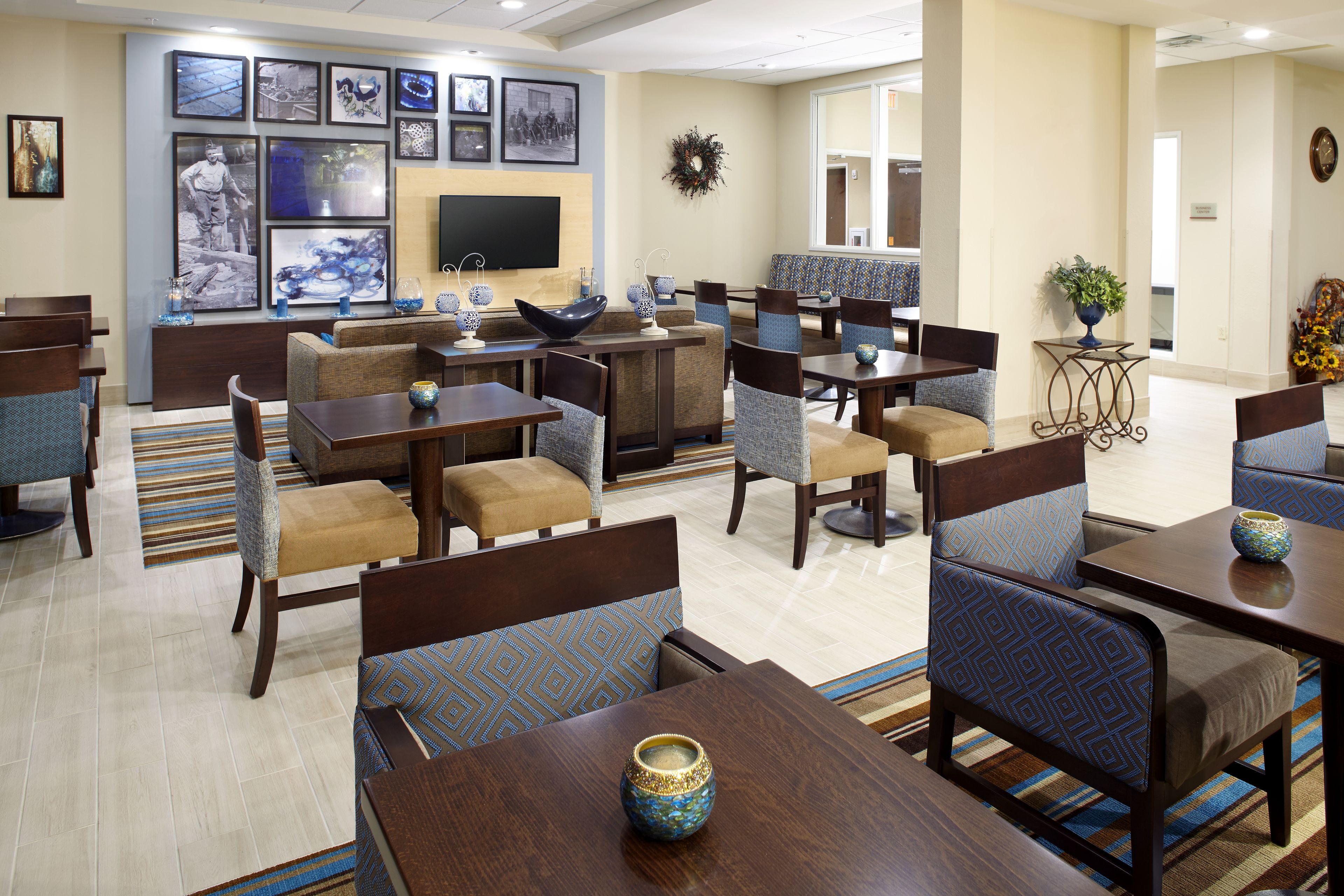 A hotel lobby with a seating area, a television, and framed pictures on the wall.