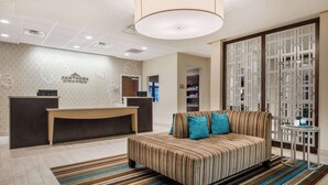 A hotel lobby with a reception desk, a sofa with striped upholstery, and a patterned rug.