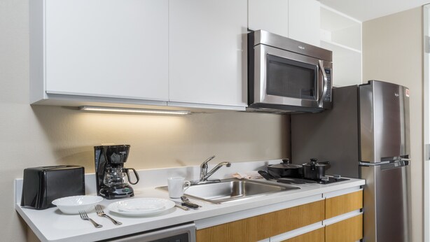 A modern kitchen with white cabinets, stainless steel appliances, a dishwasher, and a coffee maker.