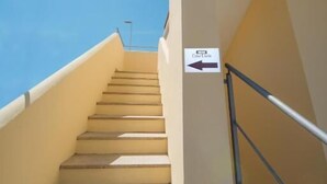 A set of outdoor stairs with a handrail, leading upwards, and a sign indicating the direction to the local area. - B&B Lucia (Olbia)