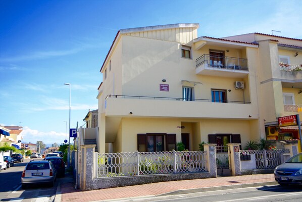 A multi-story building with a ground-level entrance, a balcony on the second floor, and a sign indicating a pizzeria. - B&B Lucia (Olbia)