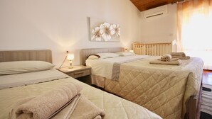 A hotel room with two beds, a nightstand with a lamp, a wall-mounted air conditioner, and a window with curtains. - B&B Lucia (Olbia)