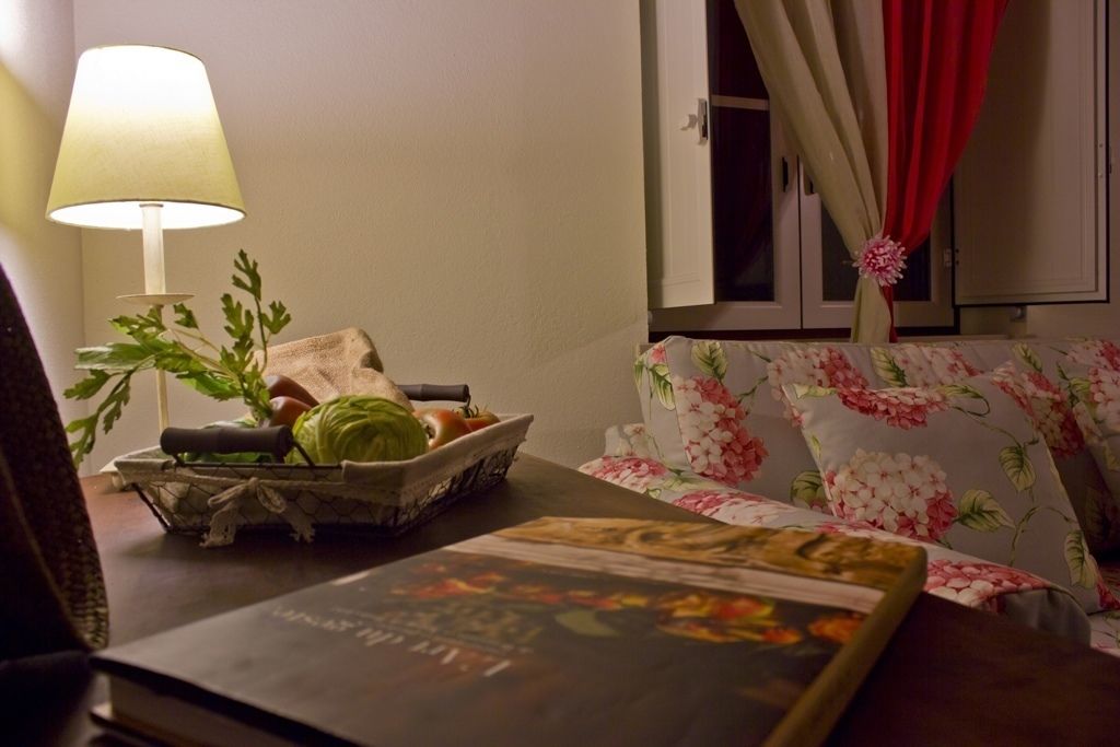 Una habitación con una cama, una mesita de noche con una lámpara, una cesta de frutas y un sofá estampado con motivos florales.