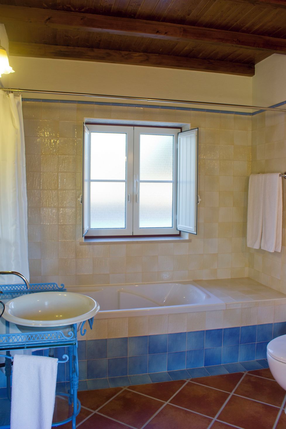 Un baño con bañera, ventana y lavamanos.