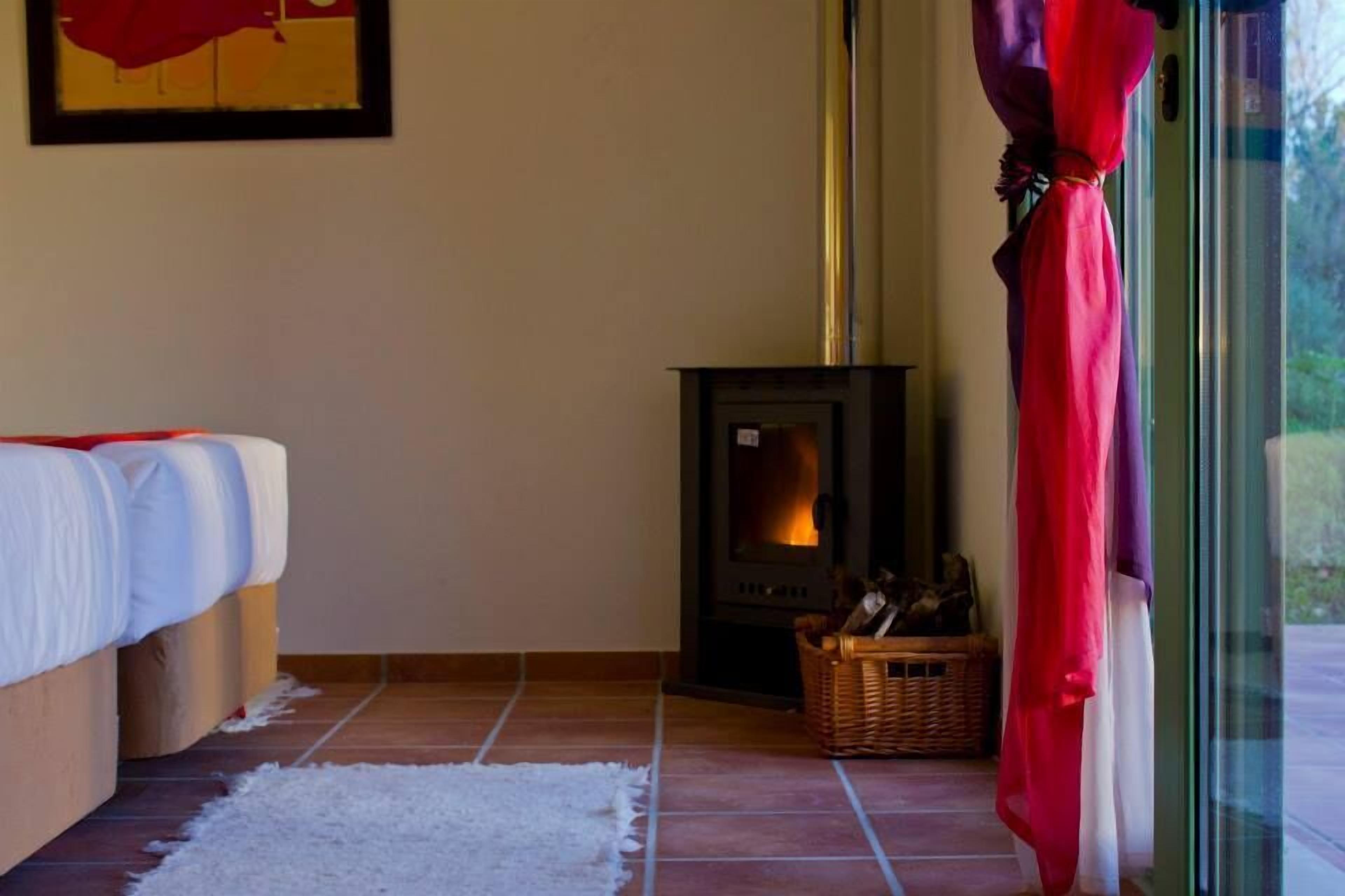 Een gezellige kamer met een bed, een open haard en een raam met gordijnen.
