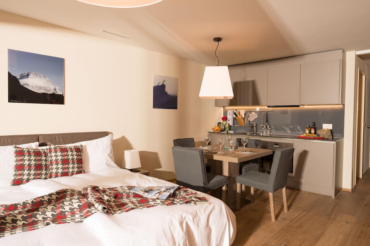 A hotel room with a bed, a dining table, and a kitchenette.