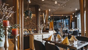 A modern restaurant interior with wooden accents, a brick wall, and a cozy seating arrangement. - Peaks Place (Laax)