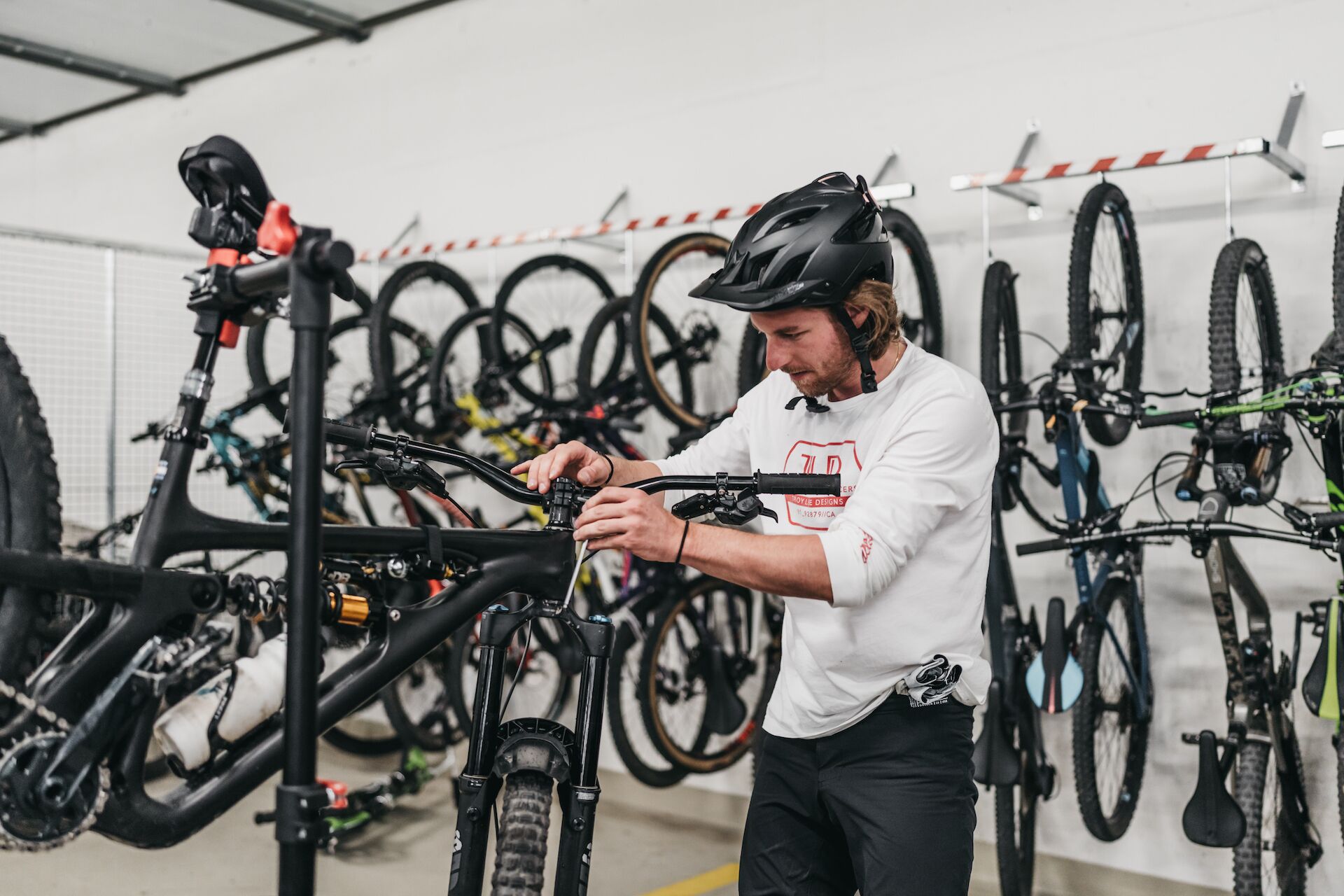 A person adjusting a bicycle in a room with multiple bicycles.