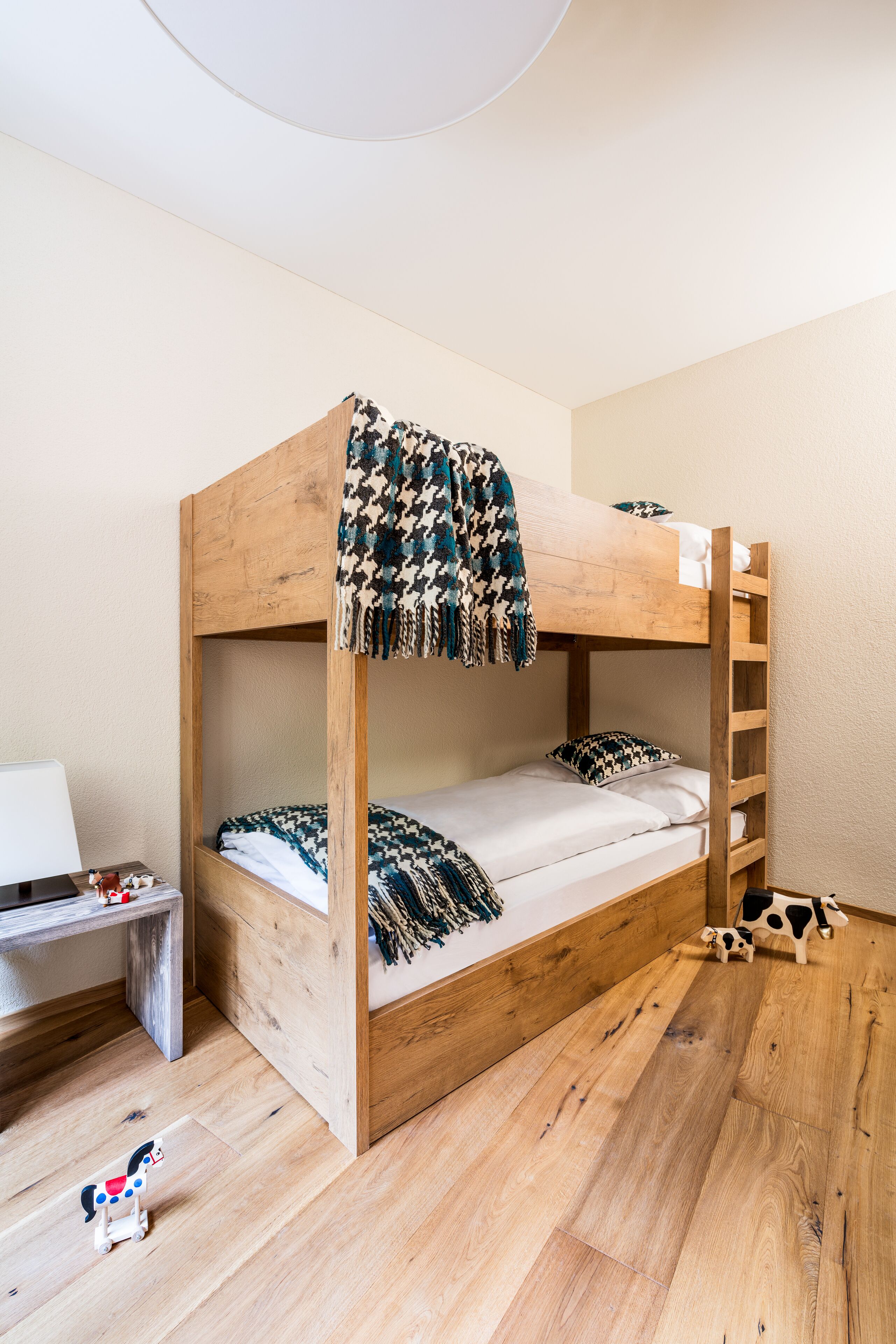 A bunk bed with a wooden frame, a small desk, and a toy horse on the floor.