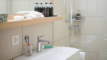 Ein modernes Badezimmer mit Waschbecken, Spiegel und Dusche in Weiß.