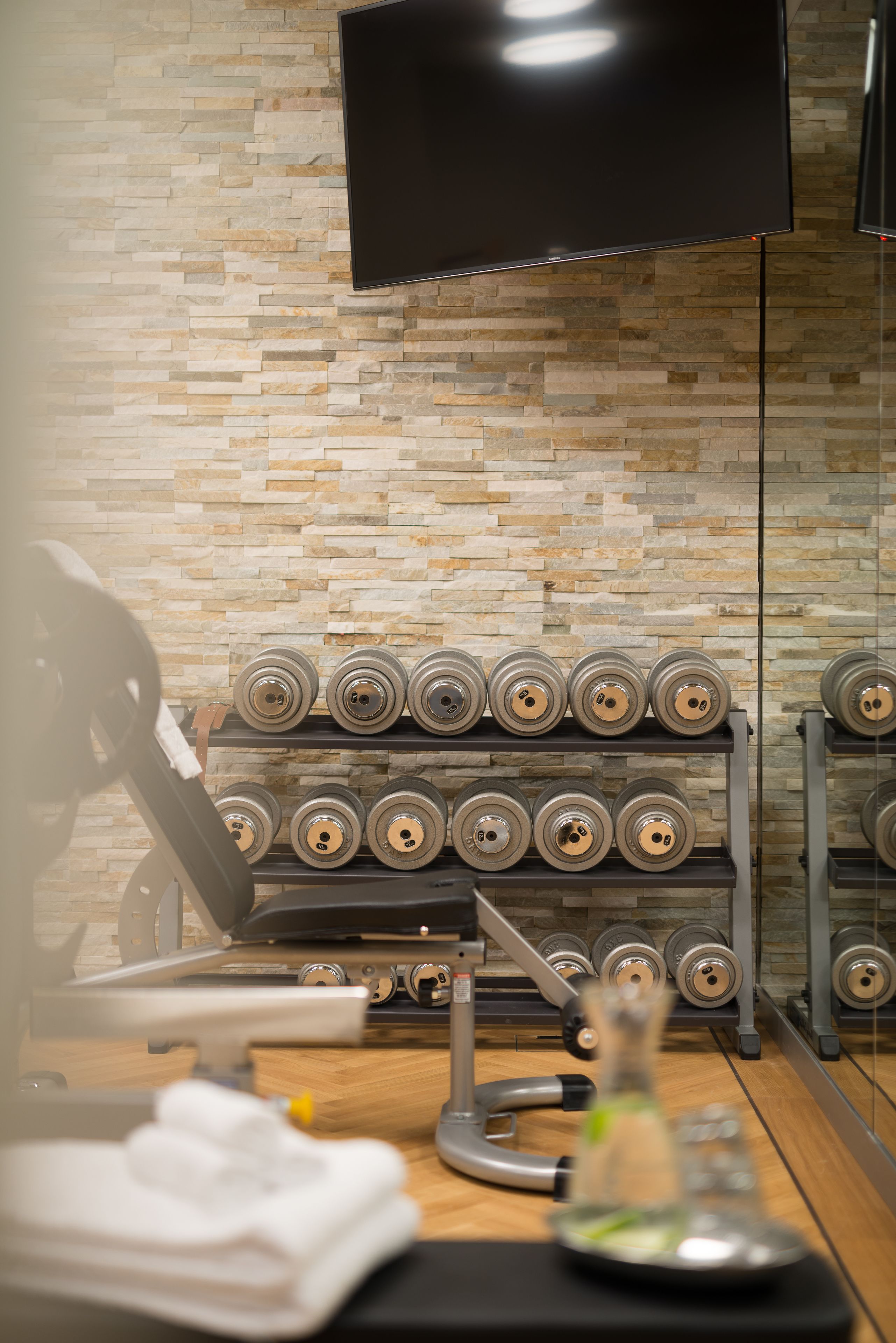 A gym with exercise equipment, a television, and a wall with a stone pattern.