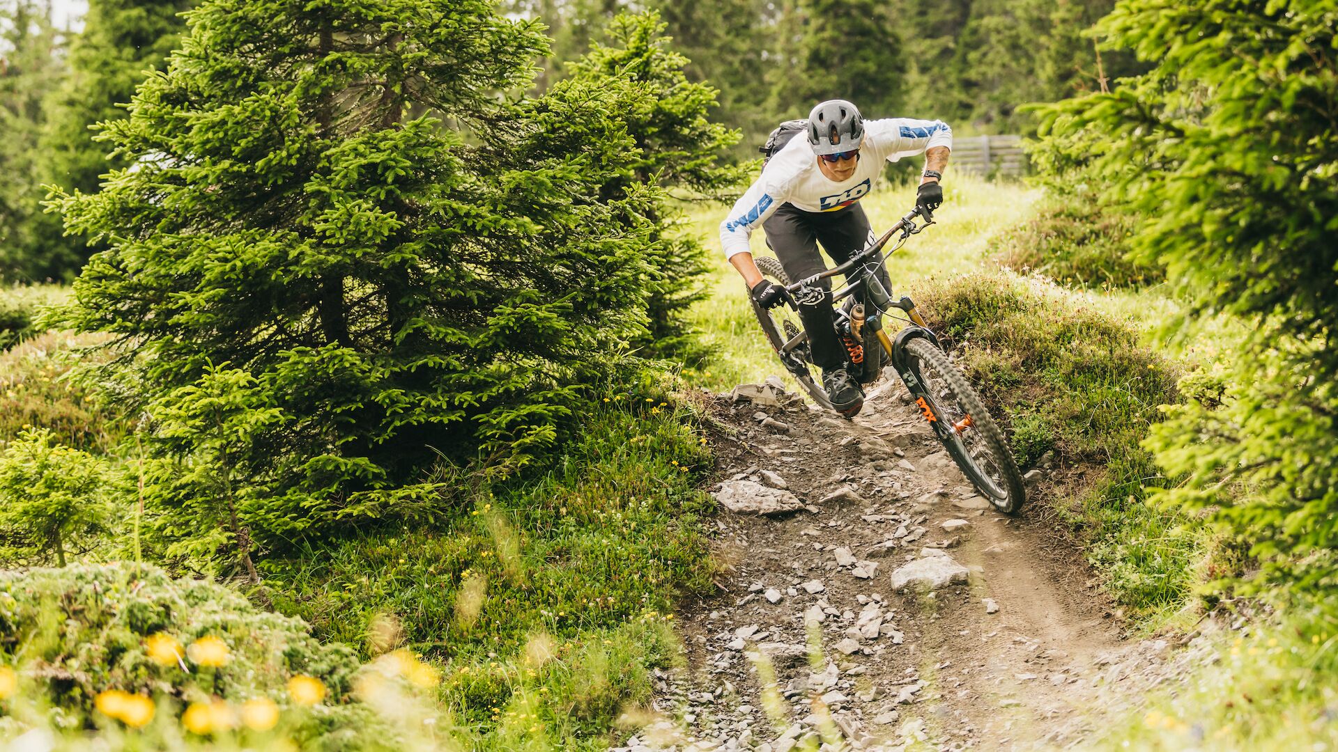 Ein Mountainbiker auf einem unbefestigten Pfad, umgeben von dichtem Grün.