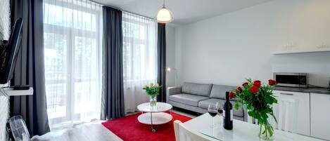 A modern living room with a sofa, a dining table, and a kitchen area.
