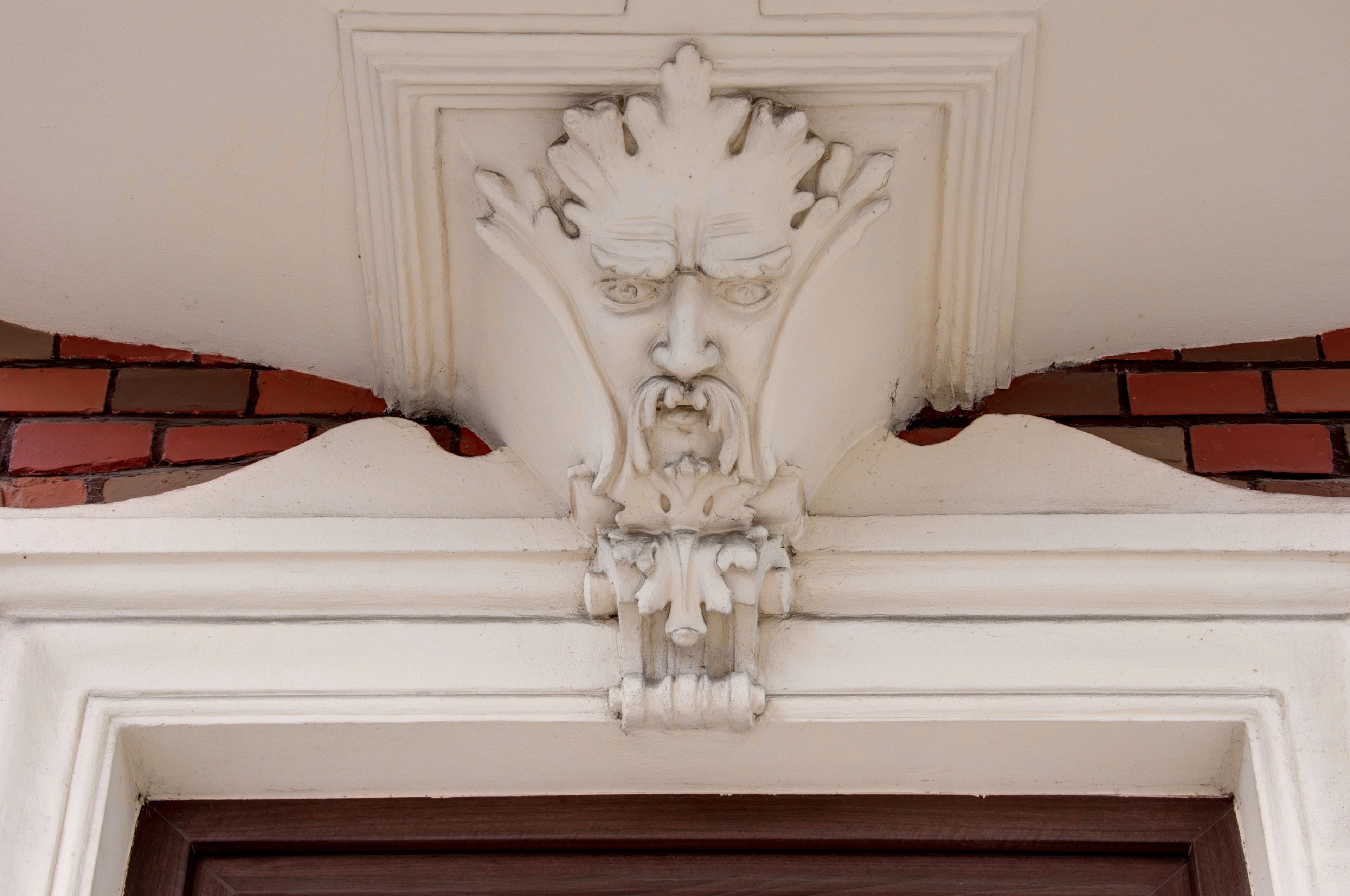 A detailed architectural carving above a door, featuring a face with a prominent nose and mouth.
