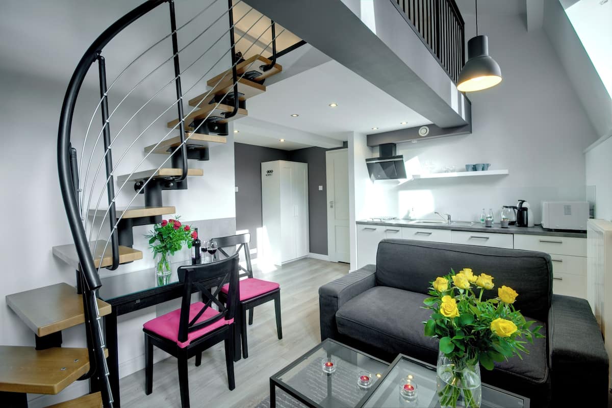 Een modern appartement met een trap, eethoek, woonkamer en keuken.