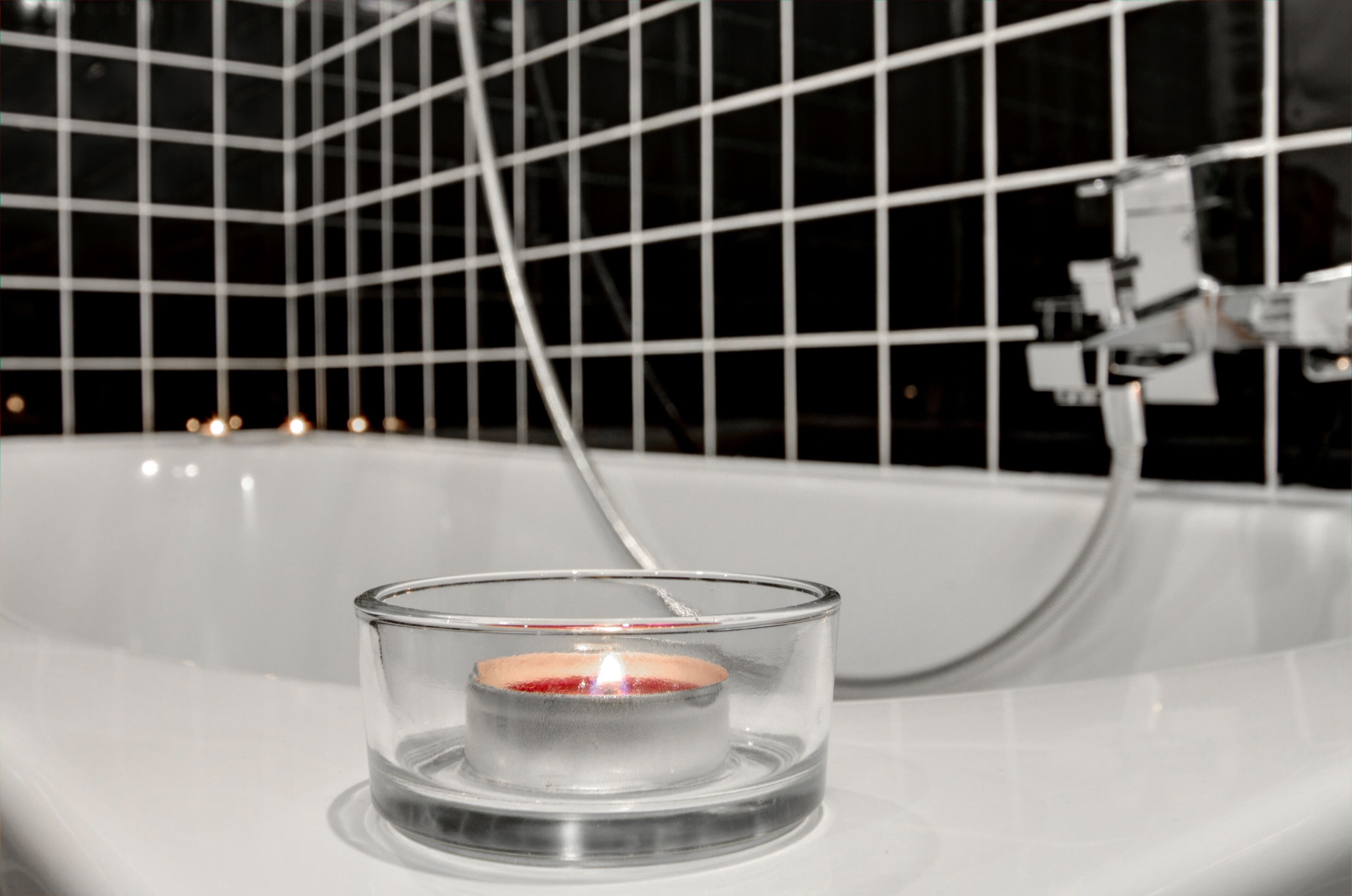 Una vasca da bagno con un porta candele in vetro contenente una candela accesa.