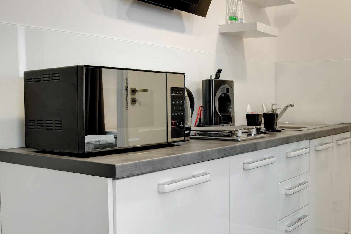 Een keuken met een magnetron, koffieapparaat en een spoelbak met kraan.