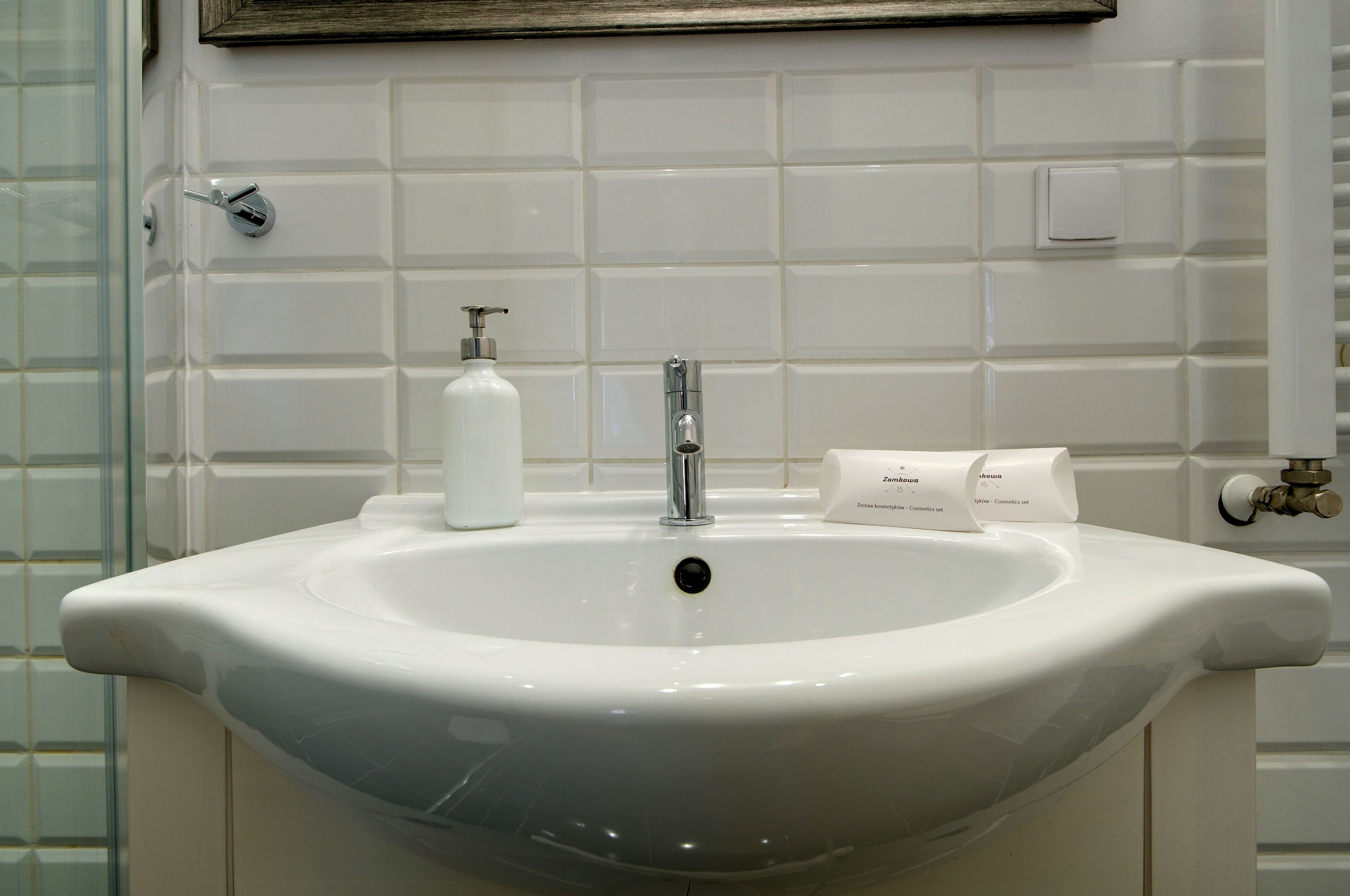 Un lavabo de salle de bain avec un robinet chromé, un distributeur de savon et une boîte à mouchoirs.