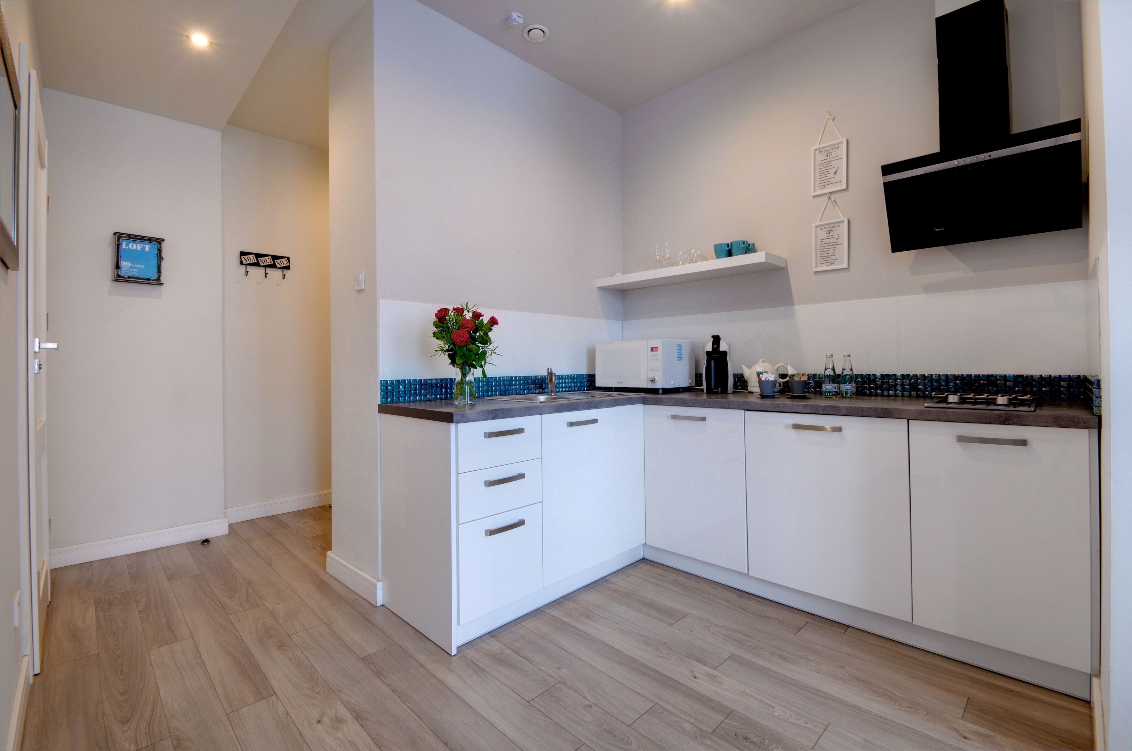 A modern kitchen with white cabinets, a built-in oven, and a stainless steel range hood.