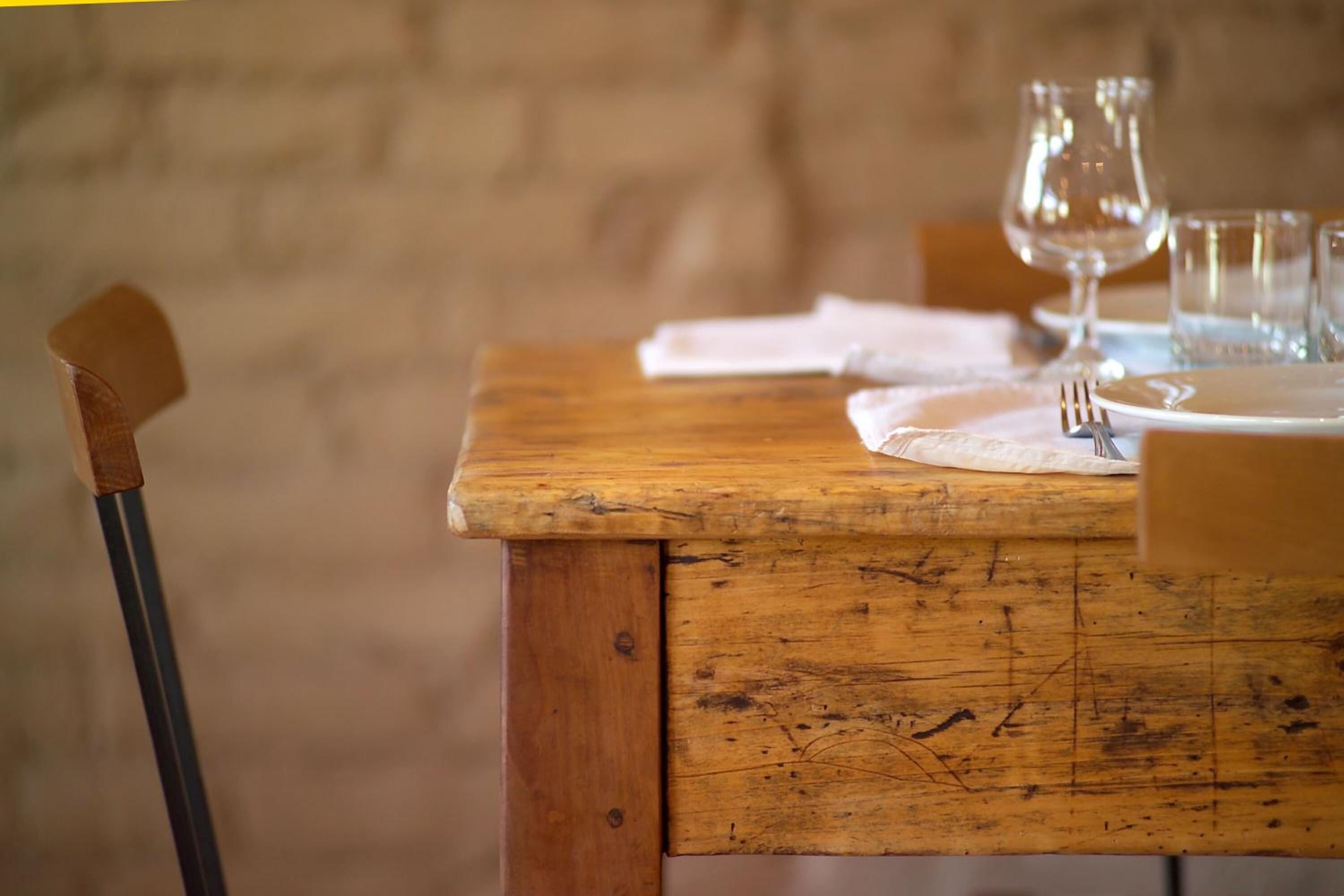 A rustic wooden table set with a white plate, a fork, and a glass.